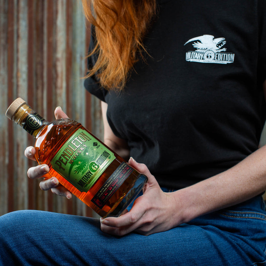 Model holding Pendleton® Whisky Military Edition Bottle while wearing Military T-Shirt