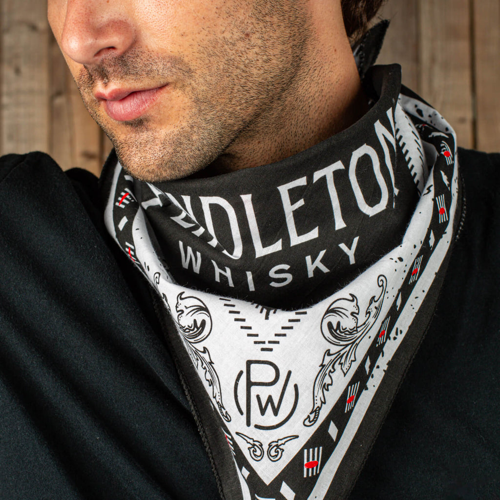 Closeup of man wearing black shirt and black, red, and white patterned Pendleton® Whisky Bandana around his neck