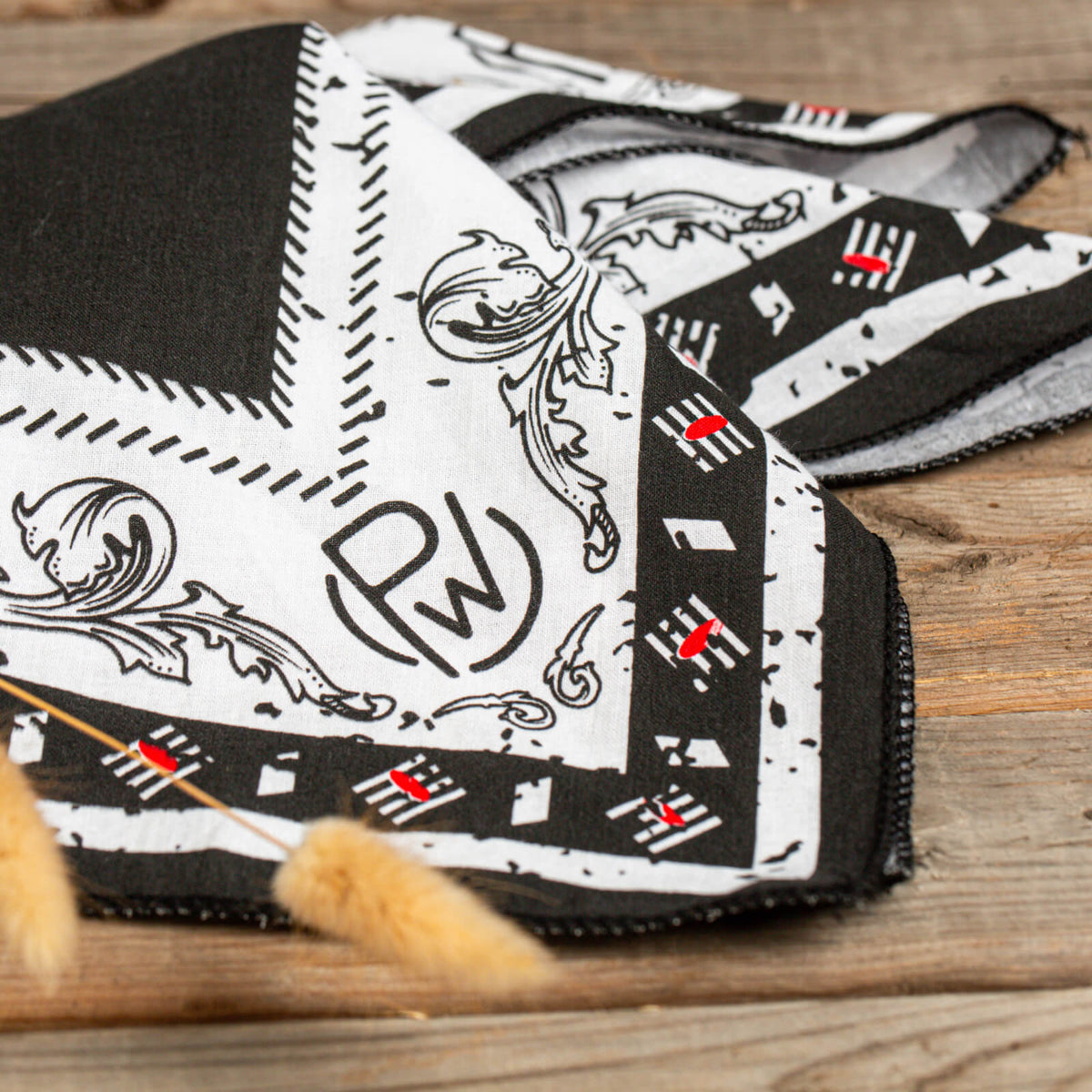 Closeup of  a folded black, red, and white patterned Pendleton® Whisky Bandana on wood surface