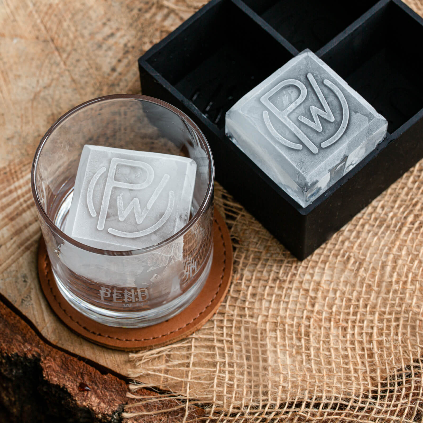 Ice Tray and Ice cube with Pendleton® Whisky logo on it within an etched rocks glass on a wood and canvas surface