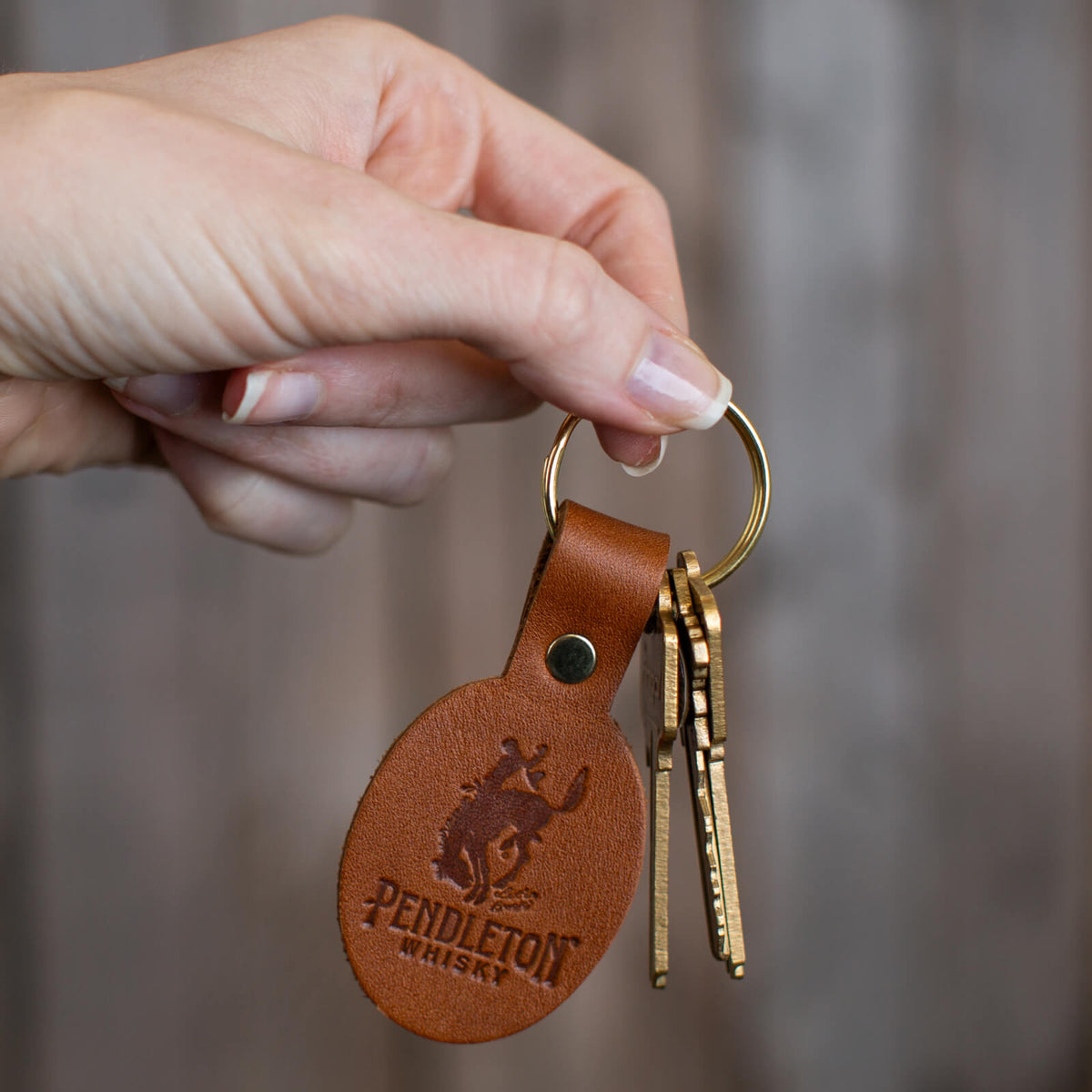 Hand holding Pendleton® Whisky leather keychain