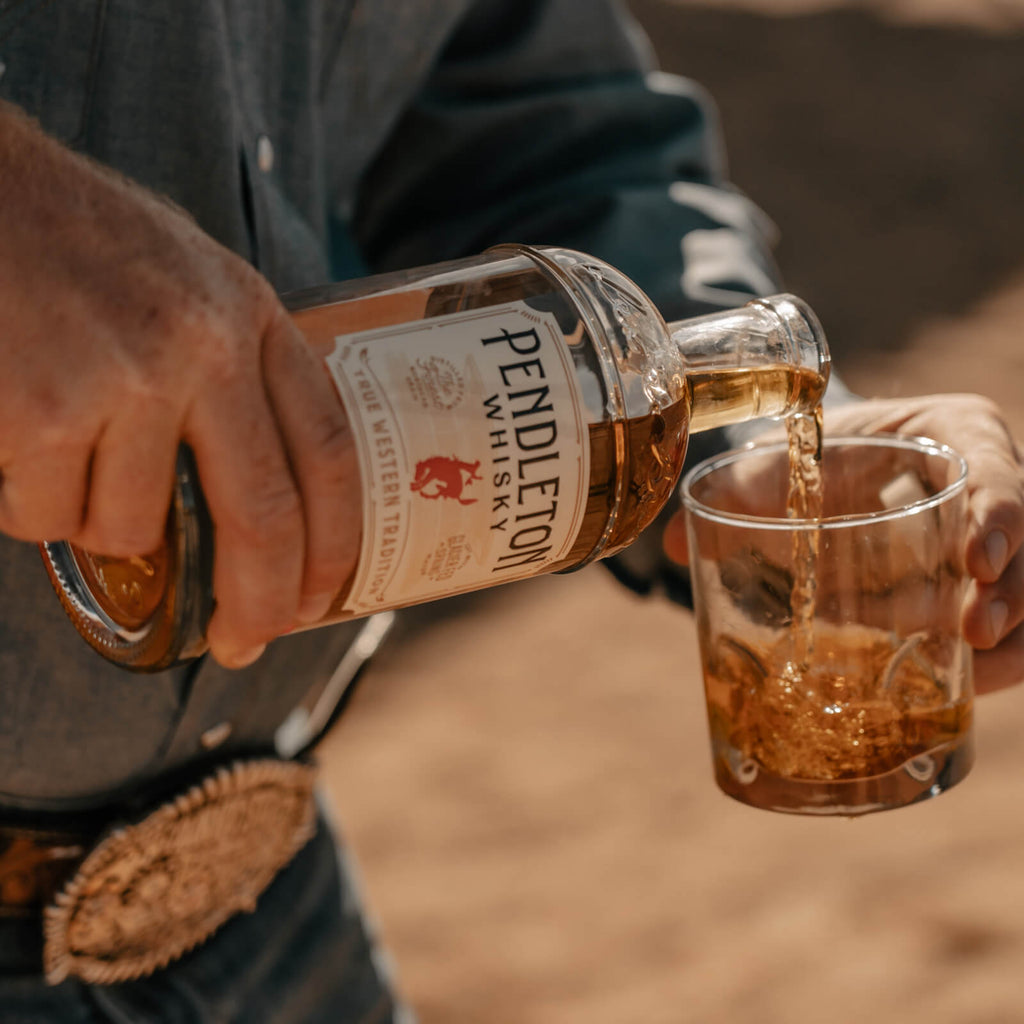Cowboy pouring Pendleton Whisky into a rocks glasses